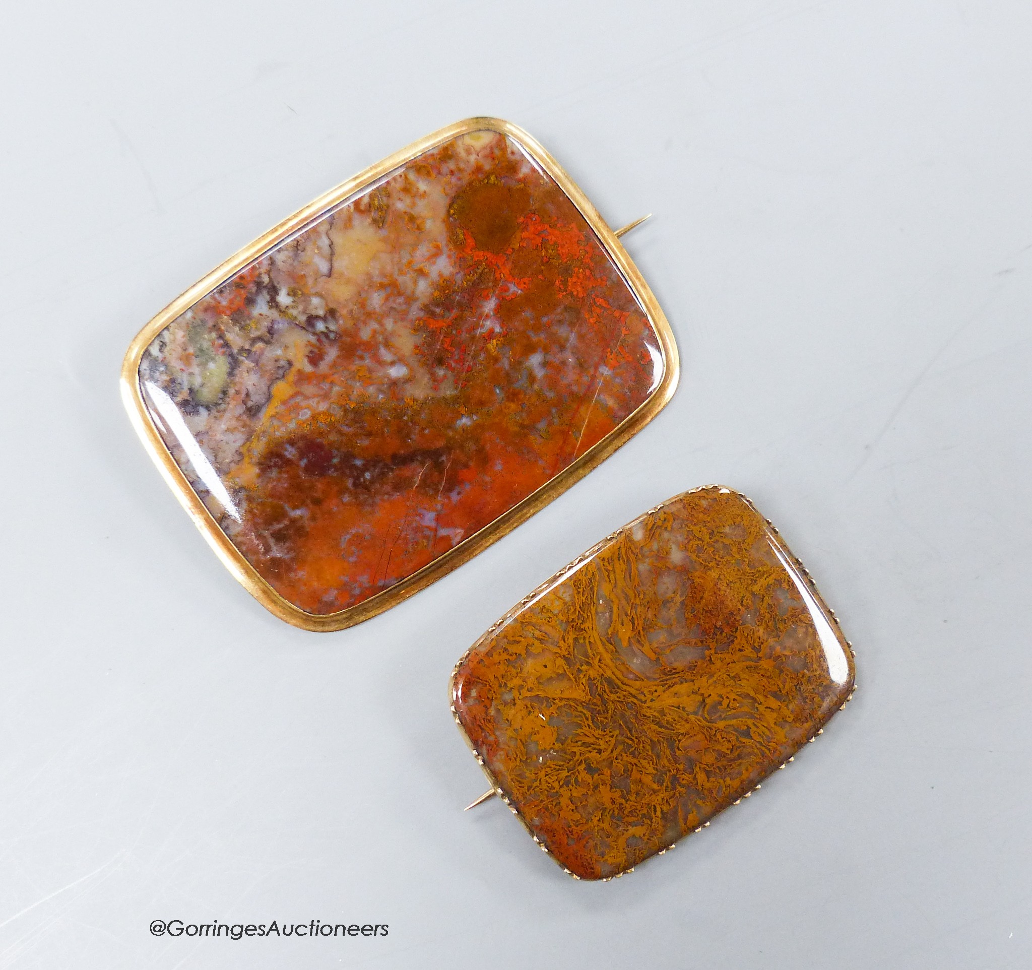 Two early 20th century yellow metal mounted agate shaped square brooches, largest 74mm, gross weight 42 grams.